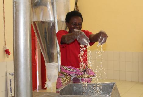 Mukasine cheerfully holds maize while working at the maize milling machine in Karongi