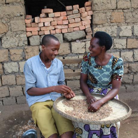 Niyonsaba having a light moment with her son while sorting beans for dinner