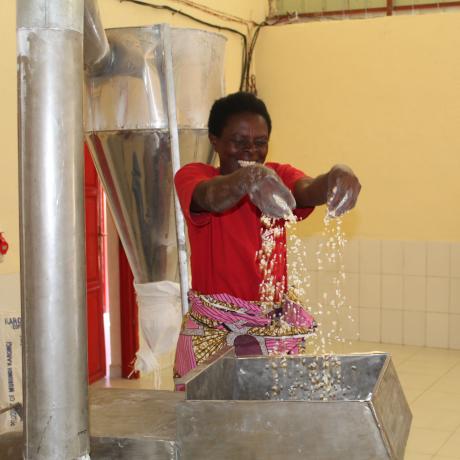 Mukasine cheerfully holds maize while working at the maize milling machine in Karongi